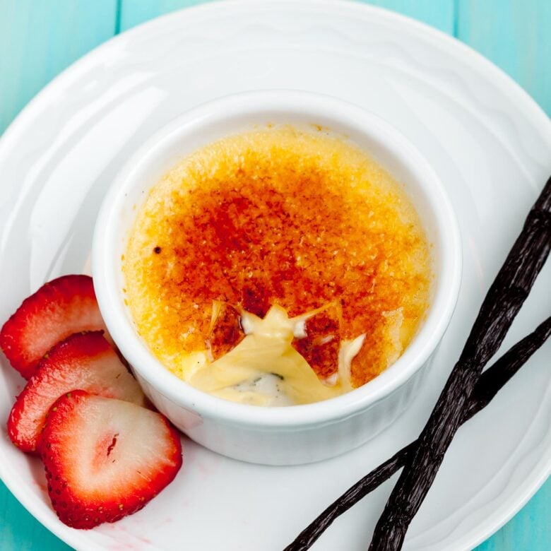 Creme Brulee in ramekin with strawberries and vanilla beans