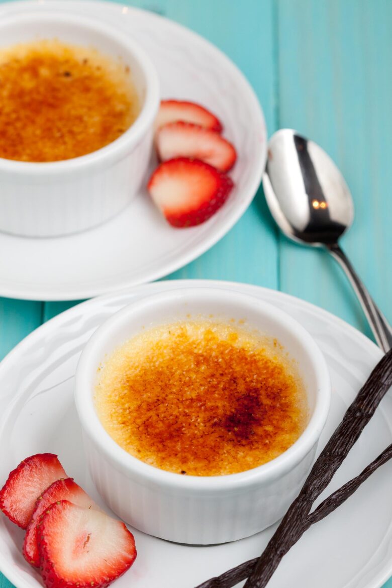 Creme brulee in ramekins with strawberries.