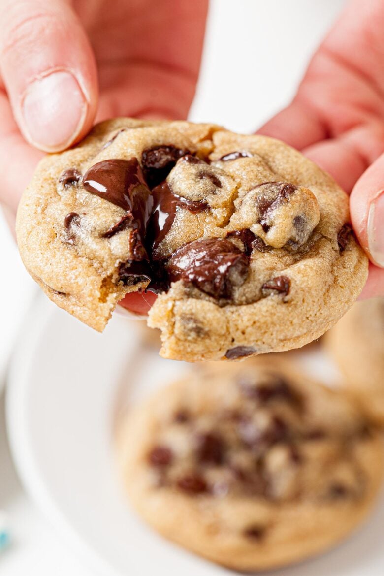 two hands pulling apart a chewy chocolate chip cookie