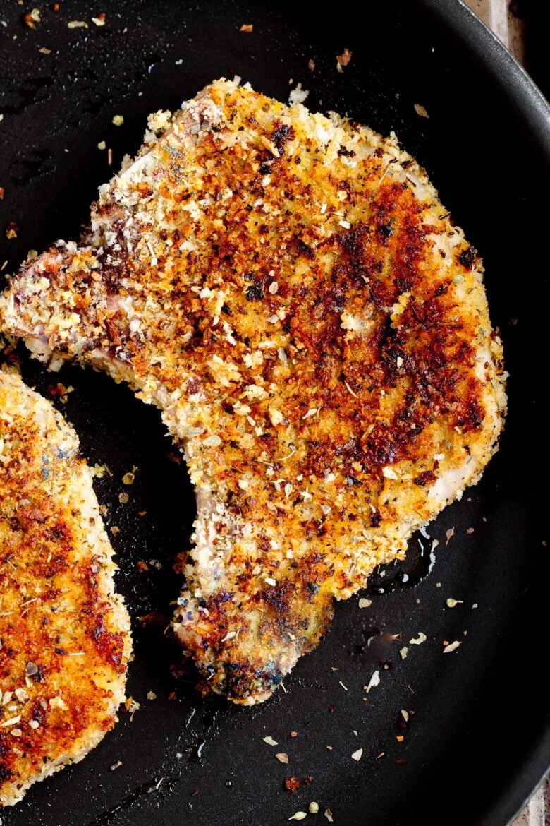 two panko breaded pork chops in a skillet