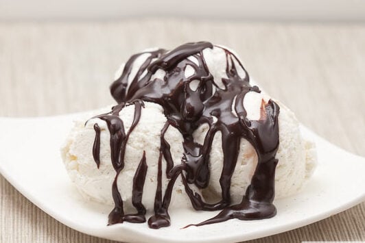 three scoops of vanilla ice cream topped with hot fudge sauce