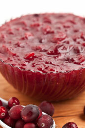 a bowl of homemade cranberry sauce with a spoonful of cranberries on the side.