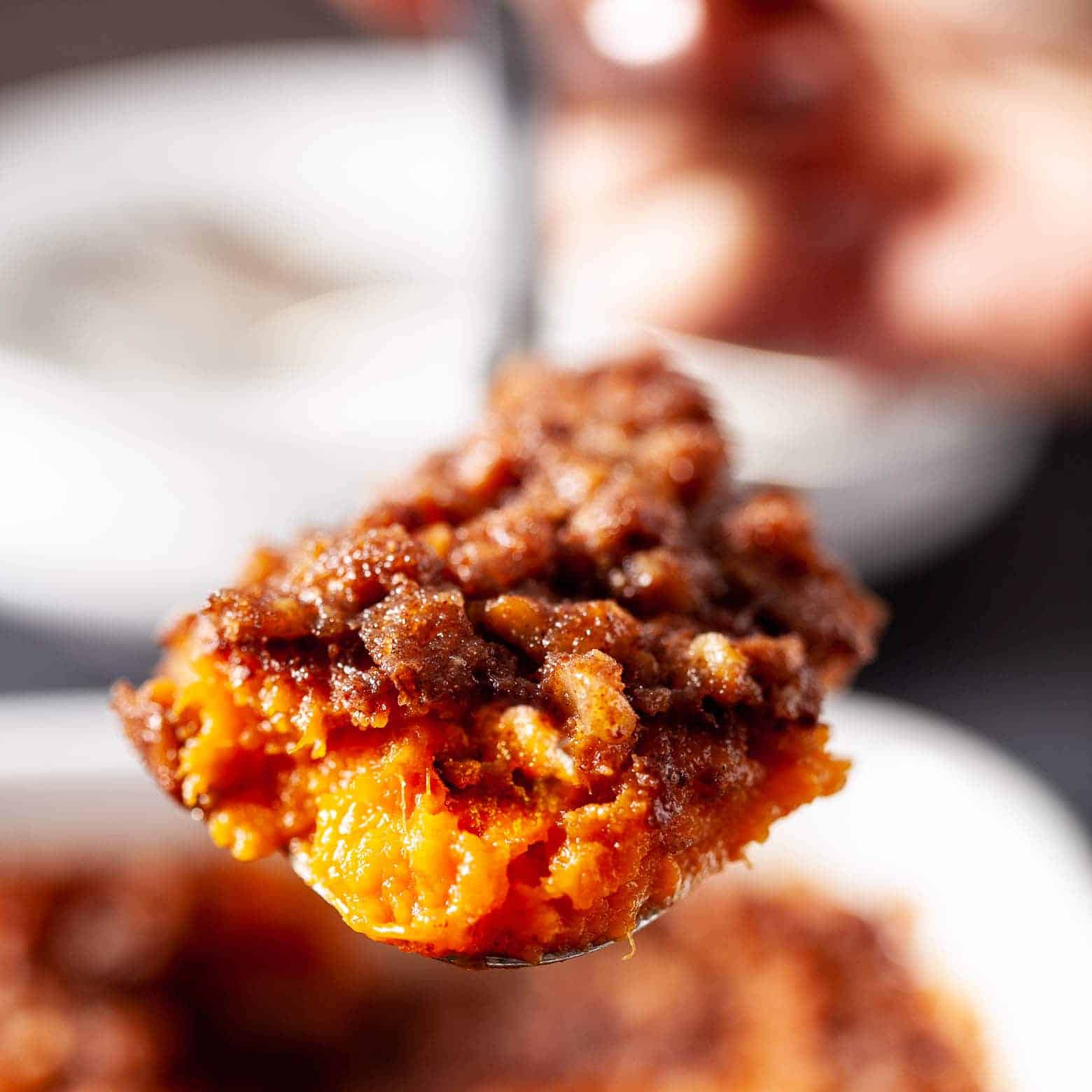 Close-up of a spoonful of sweet potato casserole with crunchy pecan topping.