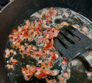 bacon being cooked in a skillet.