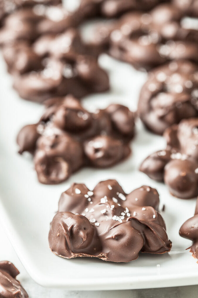chocolate almond clusters with sea salt on a white plate
