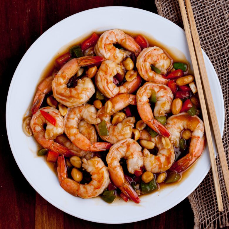 Kung Pao Shrimp in a white plate with chopsticks