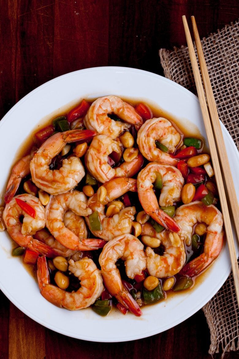 Kung pao shrimp in a white plate with chopsticks