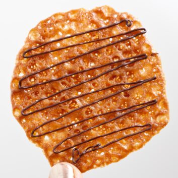 an orange lace cookie drizzled with chocolate