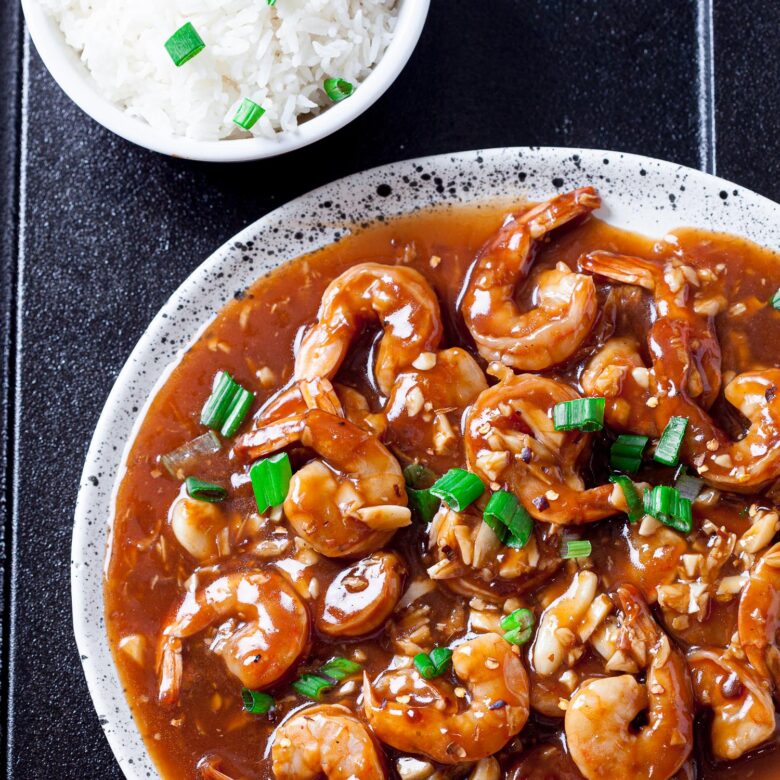 Shrimp stir fry on a plate with a bowl of rice