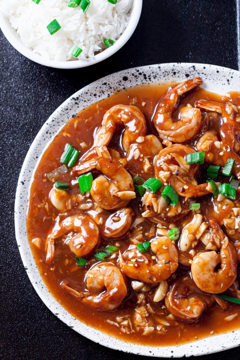 Shrimp stir fry on a plate with a bowl of rice