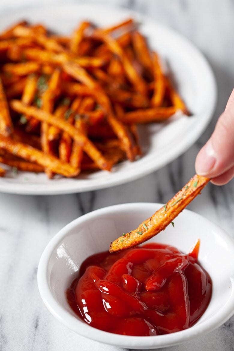 a sweet potato fry being dipped in ketchup