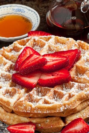 a stack of fluffy Belgian waffles topped with strawberries