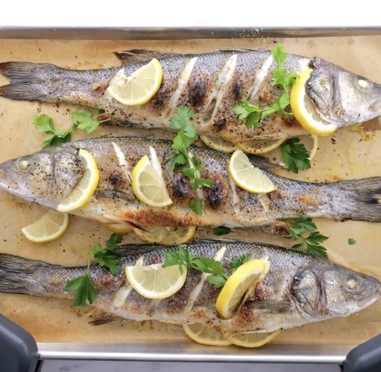 Branzino fish being roasted in a pan.