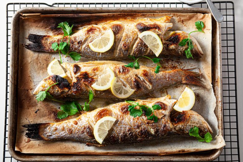 three baked branzino filets on a baking sheet