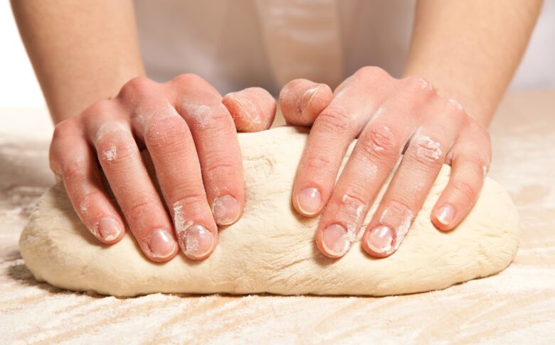 two hands kneading dough.
