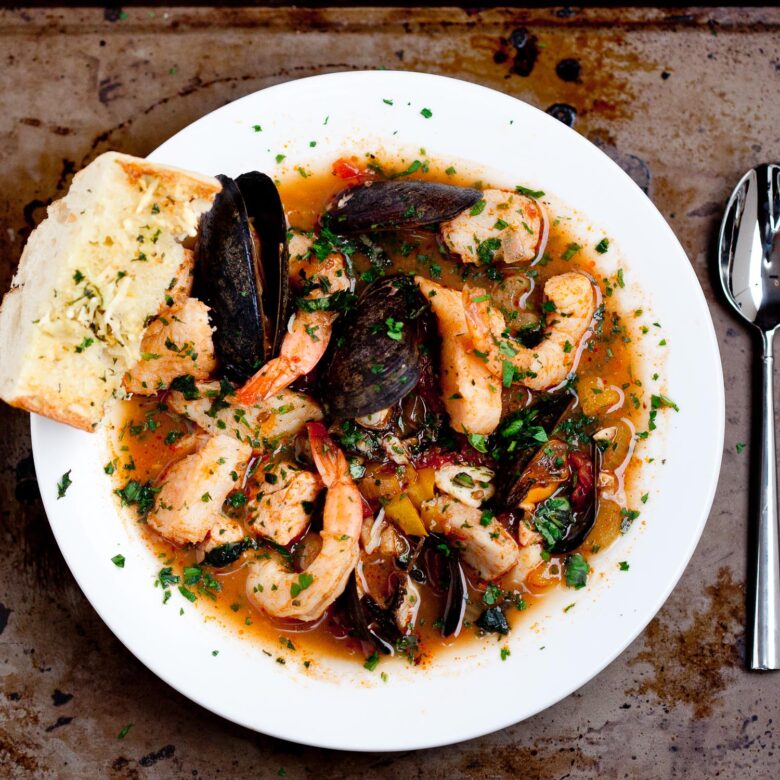 a bowl of seafood stew with a piece of crusty bread on the side