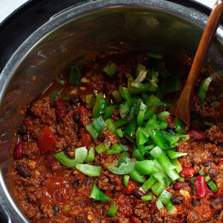 vegetables being stirred into chili in an Instant Pot