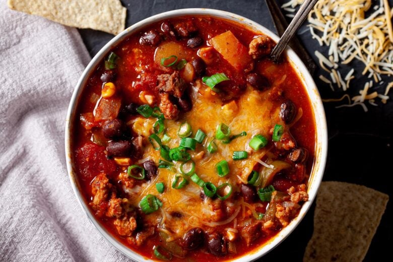 a bowl of chili topped with cheese and green onions