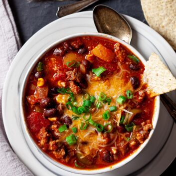 instant pot chili with a tortilla chip sticking out and a spoon on the side