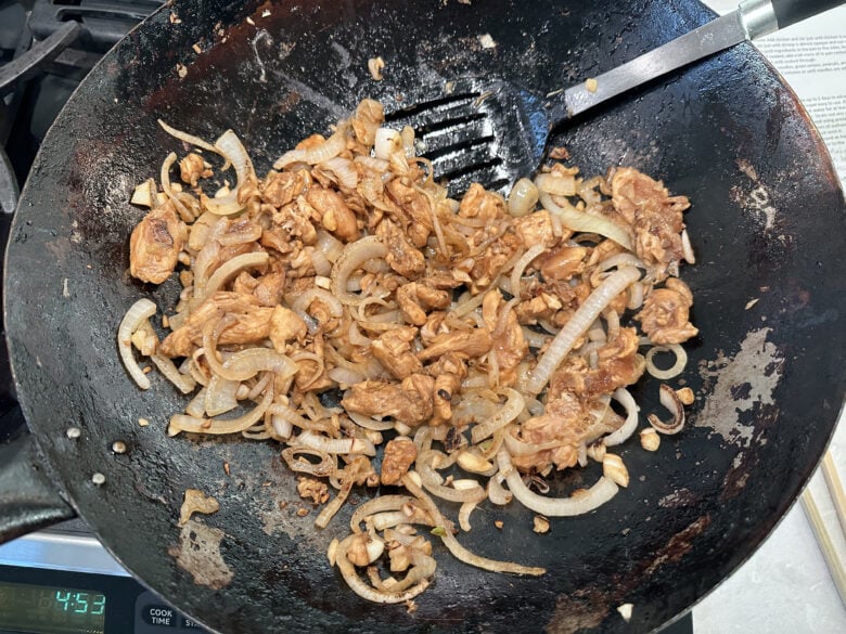 chicken and shrimp being cooked in a skillet for pad thai