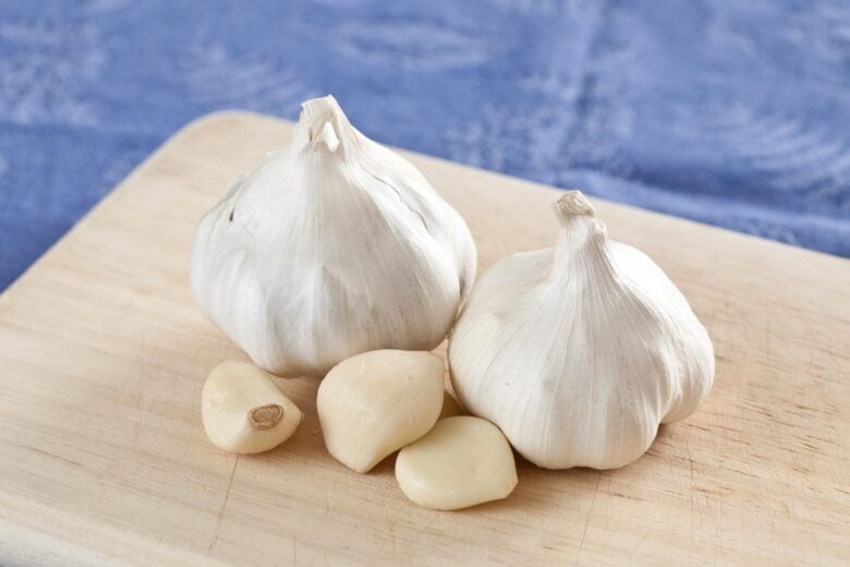 two whole heads of garlic on a cutting board