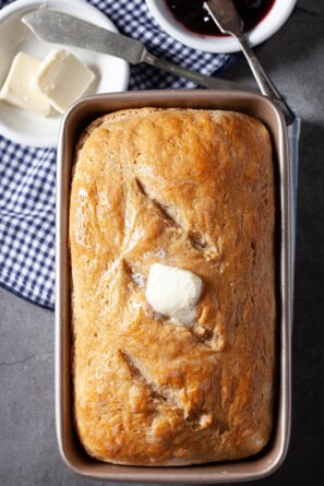 Baked sourdough bread in the pan with butter on top.