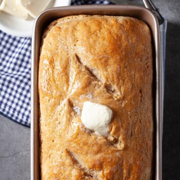 Baked sourdough bread in the pan with butter on top.