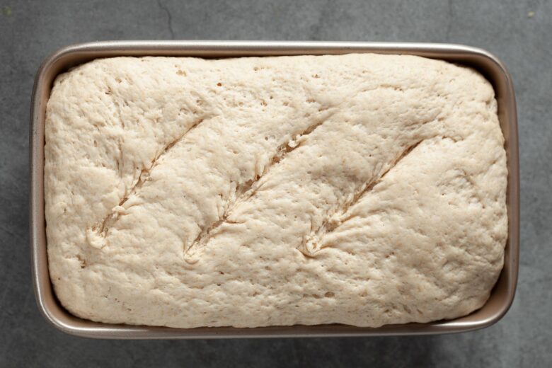 Unbaked sourdough bread in the pan and scored.