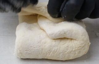 Folding rolled out buttermilk biscuit dough in on itself to form a ball.