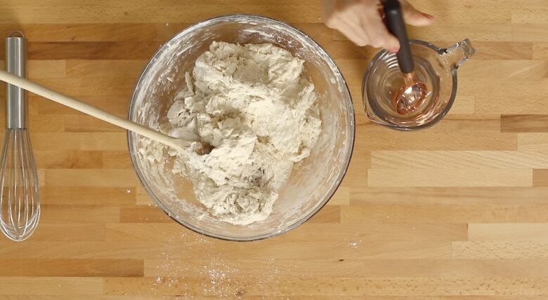 French bread dough being formed by adding a tablespoon of water at a time