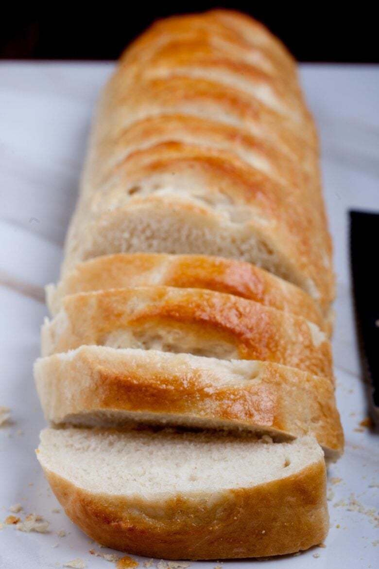 A loaf of sliced French bread on a marble table