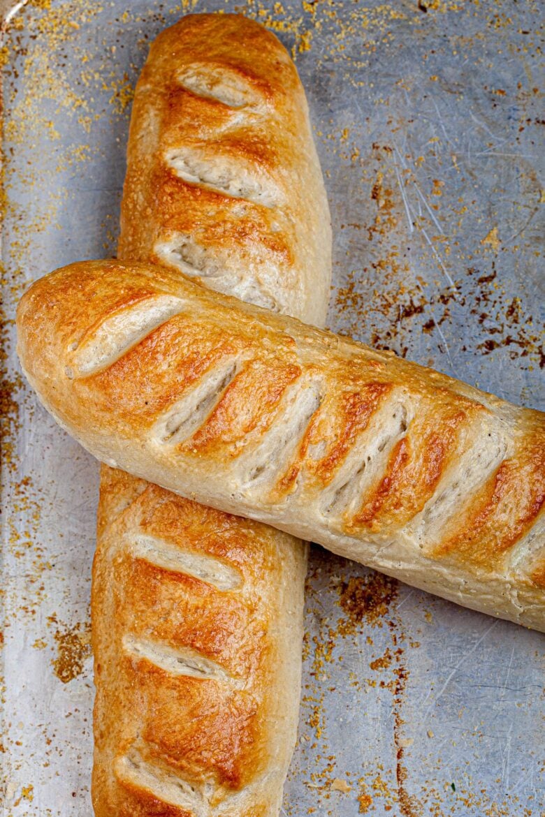 Two loaves of crispy french bread on a sheet pan