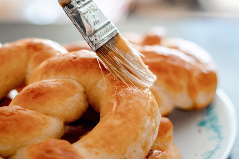 soft homemade pretzels with butter being brushed on