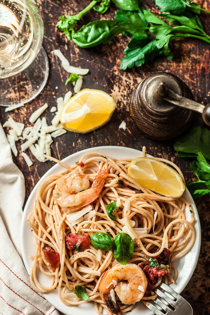 Shrimp Scampi and pasta vibrant with spring colors on a white plate with lemon slices