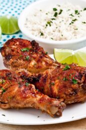 Baked Tandoori Chicken on white plate with a bowl of basmati rice on the side