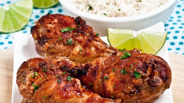 Baked Tandoori Chicken on white plate with a bowl of basmati rice on the side