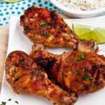 Baked Tandoori Chicken on white plate with a bowl of basmati rice on the side