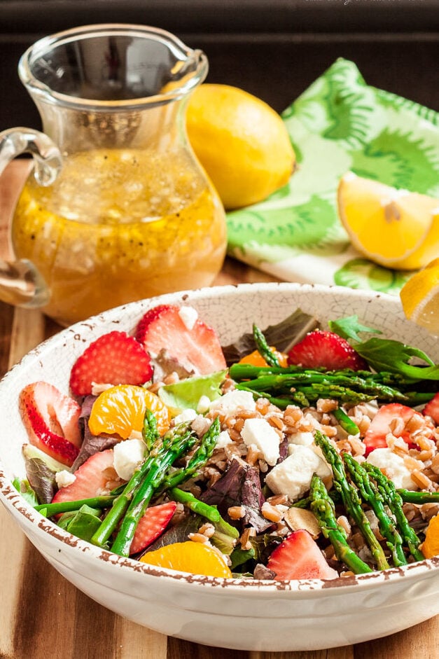Strawberry asparagus and farro salad tossed in a bowl with vinaigrette dressing