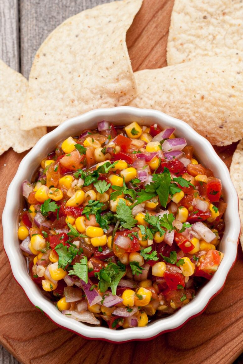 Corn Salsa in a bowl with tortilla chips on the side.