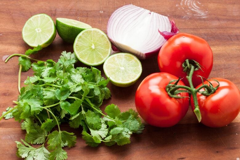 salsa ingredients including cilantro, tomatoes, limes, and red onion. 