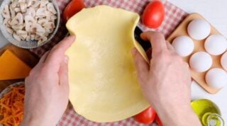 Uncooked pie crust being placed into the baking dish.