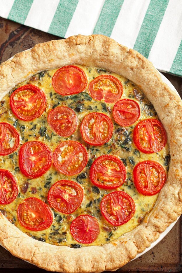 Cooked spinach quiche in the pan topped with tomatoes