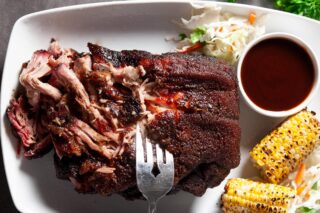smoked pork butt on a white plate with corn