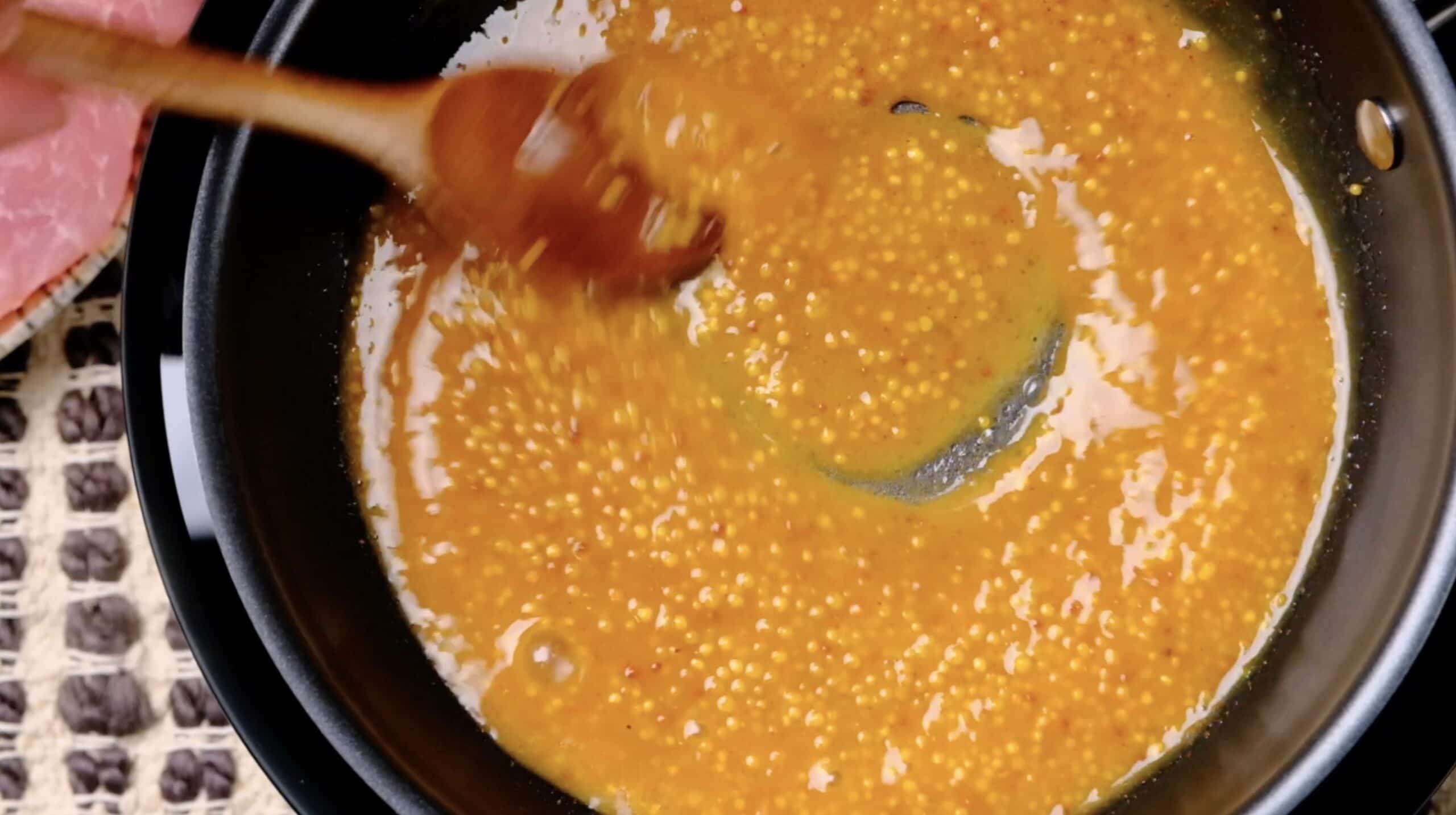 Pork chops honey mustard sauce in pan.