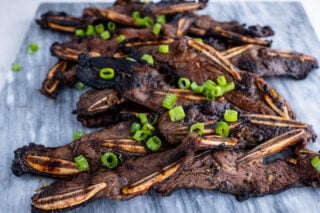 Kalbi beef grilled with green onions on white plate