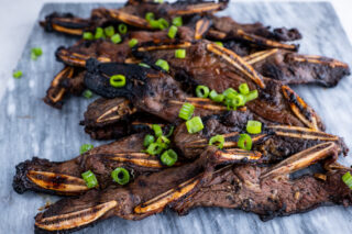 Kalbi beef grilled with green onions on white plate