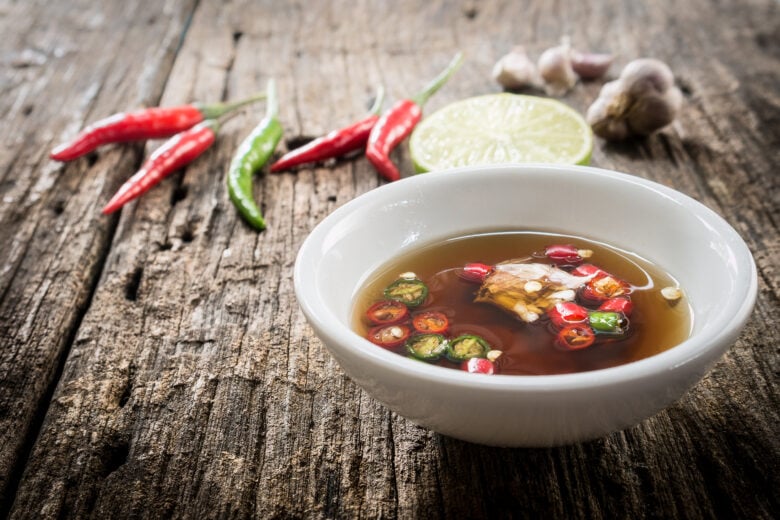 A dipping sauce made with fish sauce, chilies, and lime in a white bowl.