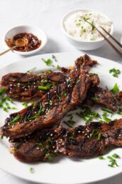 Kalbi beef short ribs on a white plate with rice and sauce