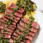 sliced grilled steaks on a plate with chimichurri sauce