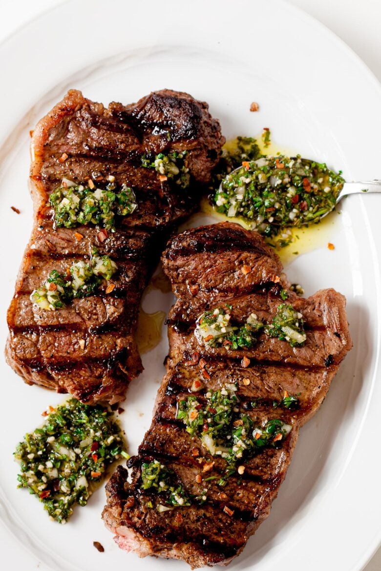 grilled steaks on a plate with chimichurri sauce
